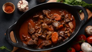 Image d’un boeuf bourguignon recette de grand-mère mijotant dans une cocotte, avec légumes et vin.